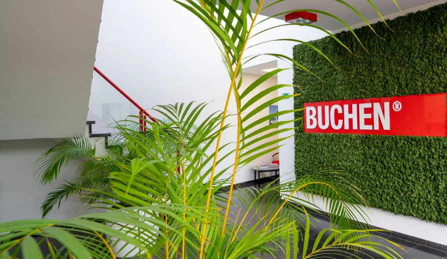 De inkomhal van het hoofdkantoor van Buchen Industrial Services met het logo omringt door groene planten aan de muur