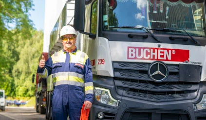 Werknemer van Buchen Industrial Services met zijn duim omhoog en naast een vrachtwagen met het Buchen-logo staat