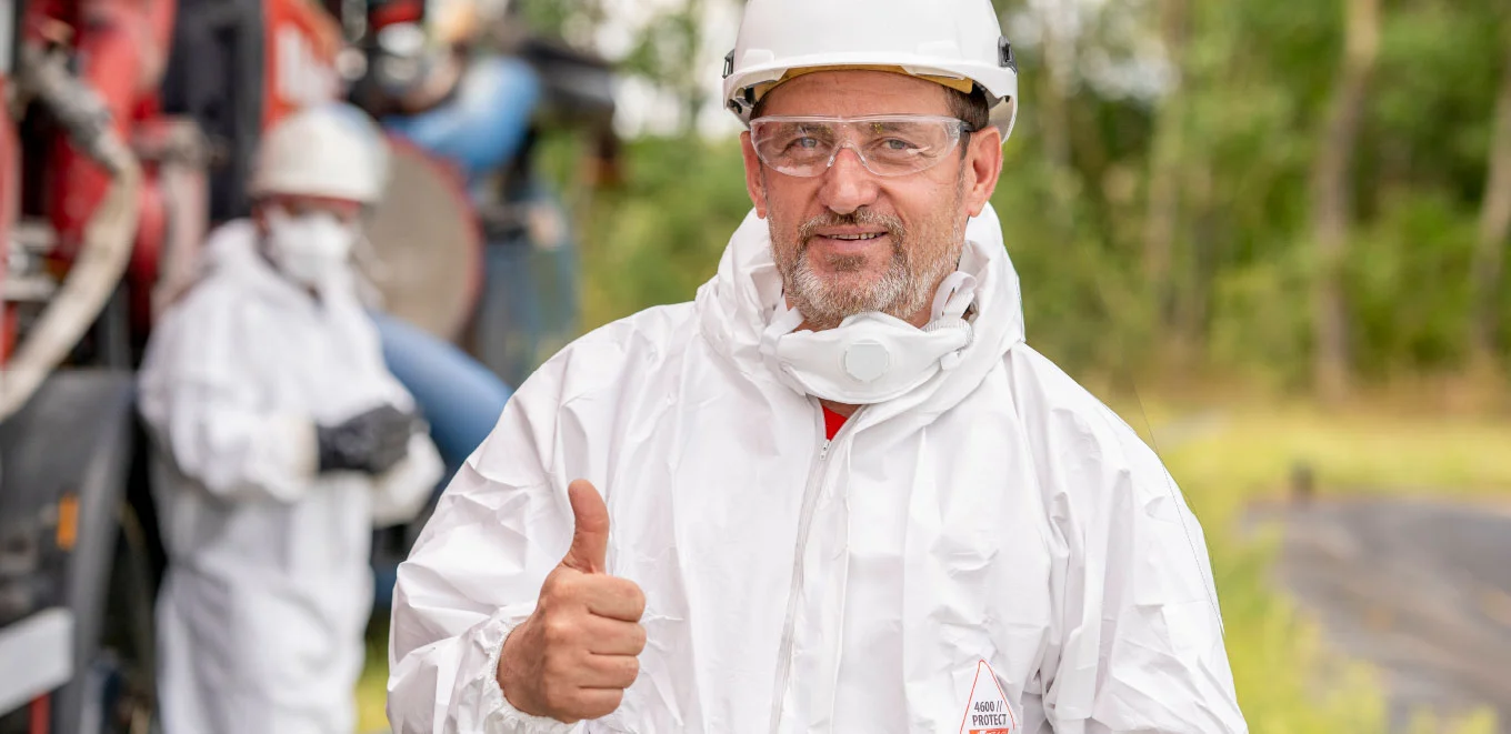 Een industriële reiniger van Buchen Industrial Services met zijn duim omhoog die persoonlijk beschermingsmateriaal draagt van Tyvek